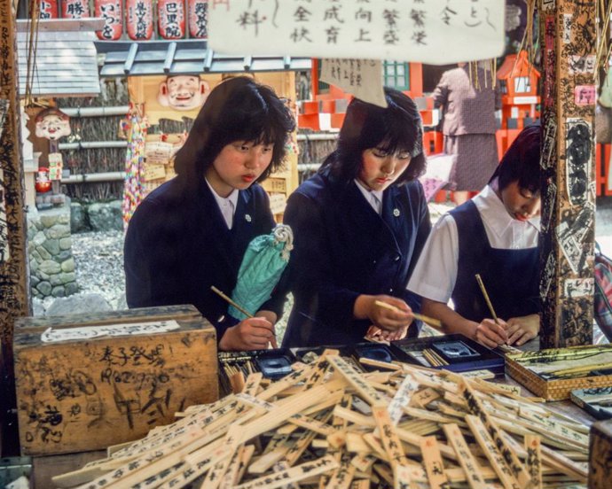 Archivo - May 6, 2021, Kyoto, Honshu, Japan: A trio of Japanese schoolgirls at the Nonomiya Shrine in Kyoto, prepare Ema, small wooden wishing plaques with prayers and wishes. A visit to Nonomiya Shrine, the Shinto Shrine to marriage, is believed to hel