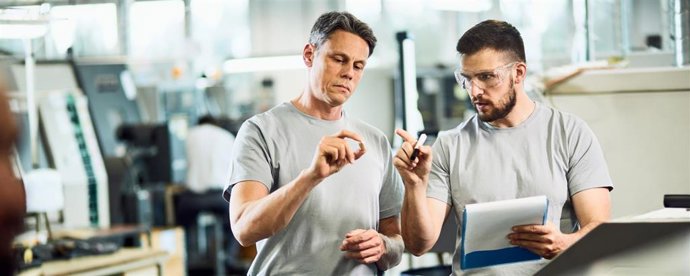 Archivo - Dos trabajadores de una industria cooperando mientras controlan la calidad de los productos manufactorados en una fábrica
