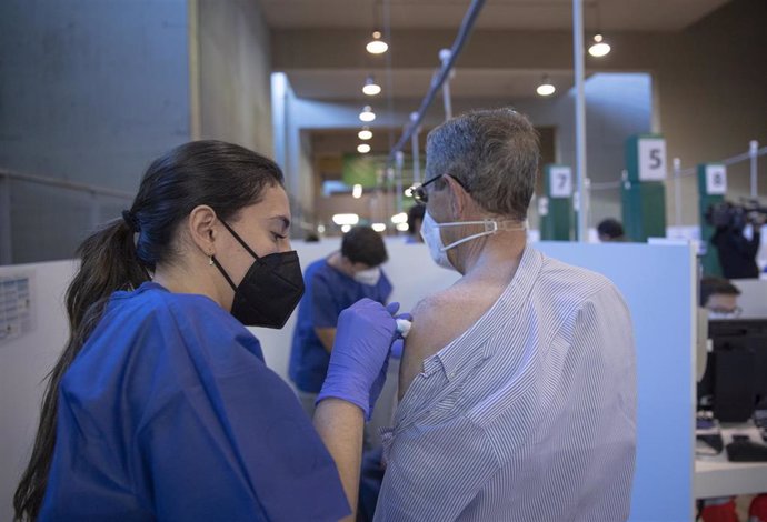 Archivo - Una sanitaria vacuna a un hombre durante la primera jornada de vacunación ante la Covid-19 en el Estadio de La Cartuja de Sevilla, (Andalucía, España), a 22 de abril de 2021.