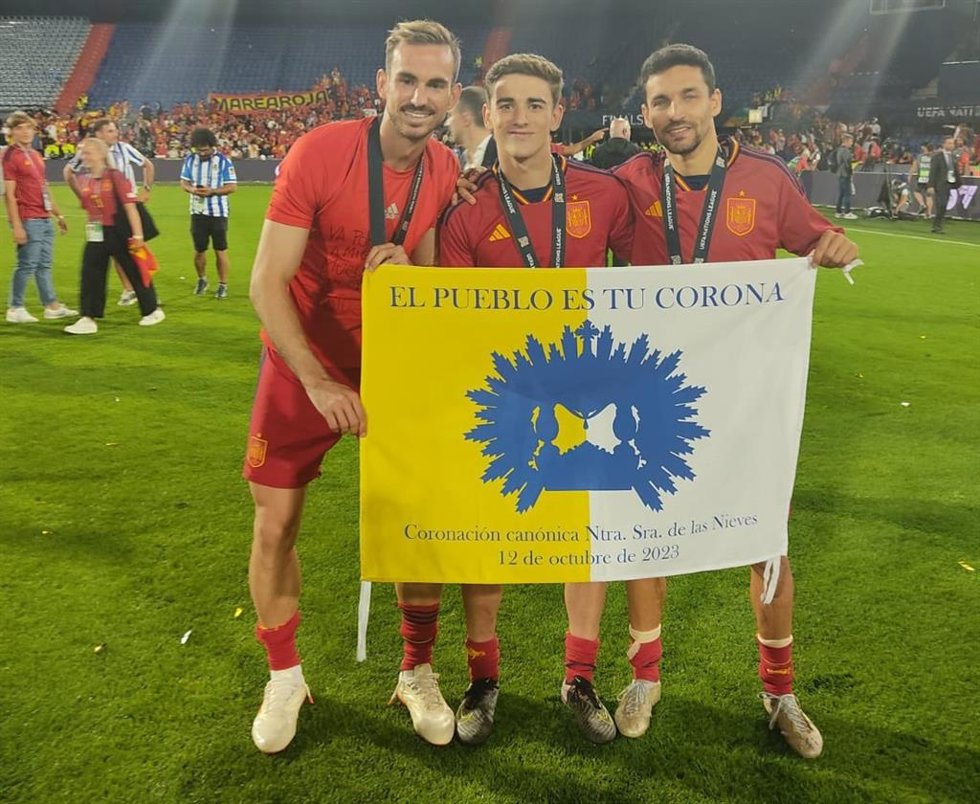 Imagen de los tres jugadores palaciegos con la bandera de la Coronación Canónica