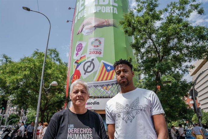 La presidenta de la Federación Estatal LGTBI+, Uge Sangil y el presidente de COGAM, Ronny de la Cruz, posan frente a la lona que Vox ha instalado en la calle Alcalá, 145, a 19 de junio de 2023, en Madrid (España). 