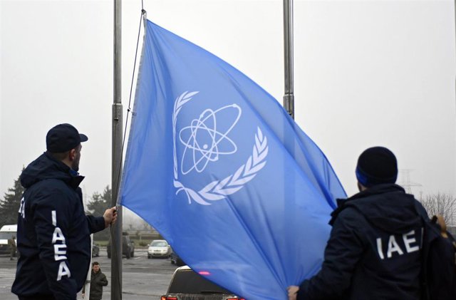 Archivo - Empleados del Organismo Internacional para la Energía Atómica (OIEA) con una bandera de la institución