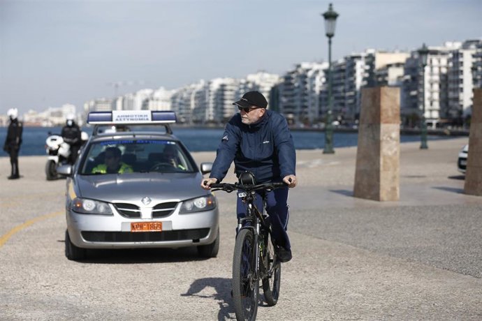 Archivo - Un hombre conduce una bicicleta frente a un coche de la Policía