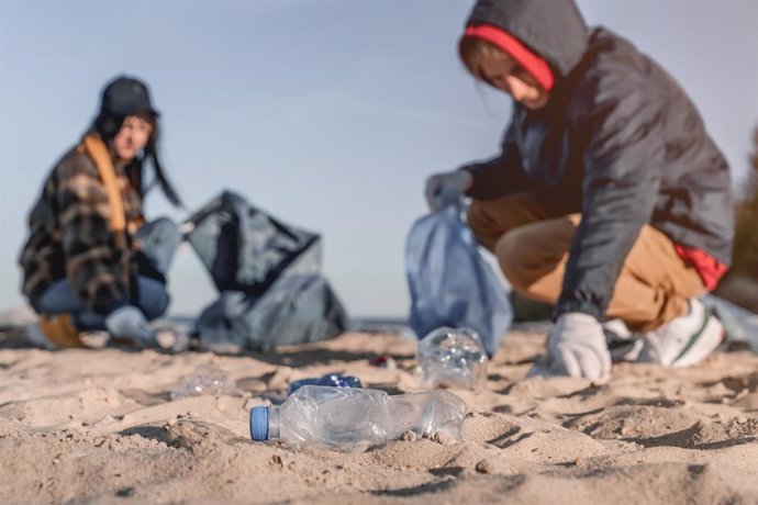 Archivo - Plásticos en la playa con grupo de voluntarios de fondo