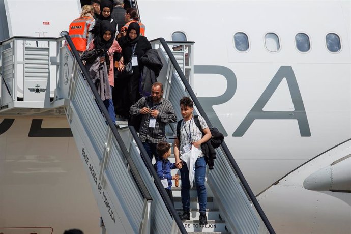 Archivo - Varias personas con niños bajan las escaleras del avión procedentes de Siria, a su llegada a la base aérea de Torrejón de ArdoZ.