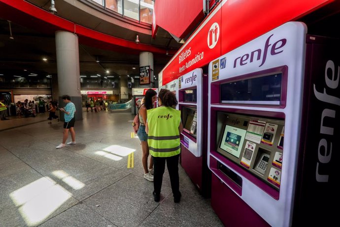 Archivo - Una trabajadora de Renfe habla con una viajera delante de las máquinas expendedoras de billetes, en la estación de Atocha, a 26 de agosto de 2022, en Madrid (España). 