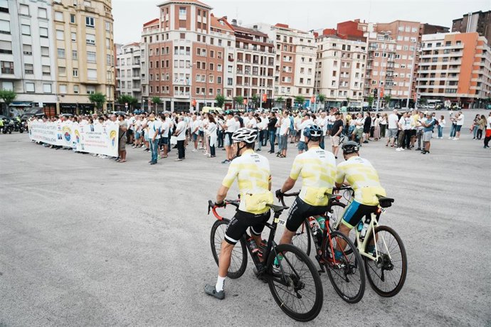 Tres ciclistas observan a un centenar de agentes de la Ertzaintza vestidos de blanco durante una concentración en la explanada de San Mamés, a 11 de junio de 2023, en Bilbao