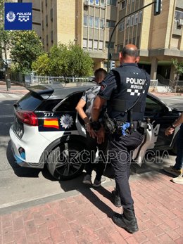 Un agente de la Policía Local de Murcia custodia al detenido