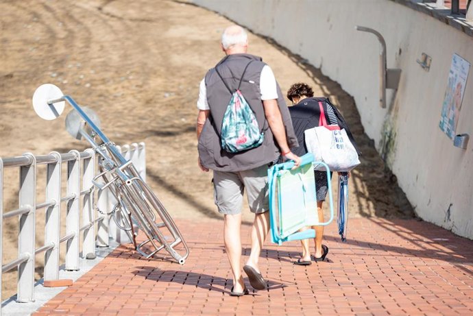 Archivo - Dos personas con sillas de la playa el día más frío del año en la playa de las Canteras, a 21 de enero de 2023, en Las Palmas de Gran Canaria, Las Palmas, Canarias (España). A partir de hoy, las temperaturas descienden por la llegada de una gé
