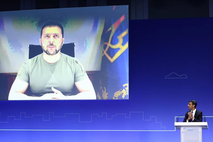 21 June 2023, United Kingdom, London: British Prime Minister Rishi Sunak (R) applauds as Ukraine's President Volodymyr Zelensky appears on the screen at the opening session on the first day of the Ukraine Recovery Conference, held at the InterContinenta