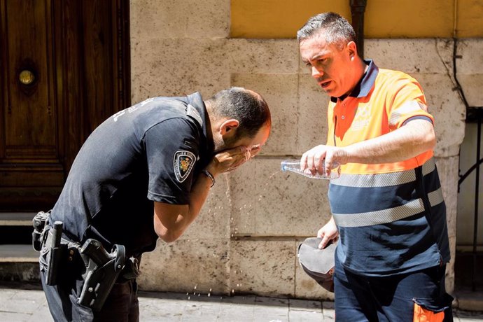 Un agente de policía se refresca la cara con agua.
