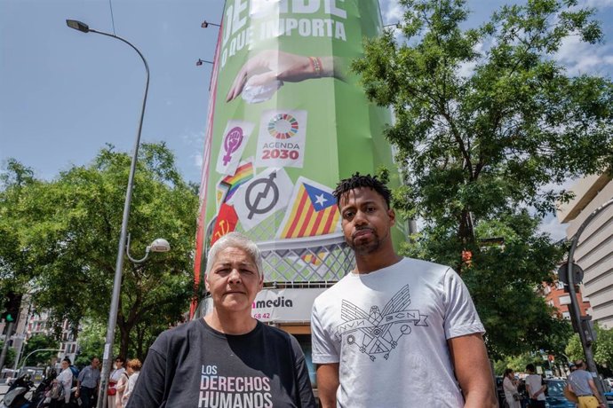 La presidenta de la Federación Estatal LGTBI+, Uge Sangil y el presidente de COGAM, Ronny de la Cruz, posan frente a la lona que Vox ha instalado en la calle Alcalá, 145, a 19 de junio de 2023, en Madrid (España).
