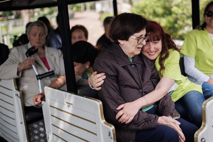 Archivo - Una trabajadora de la Residencia Casaverde de Navalcarnero abraza a una usuaria del centro, en un tren para visitar el Zoo Aquarium de Madrid.