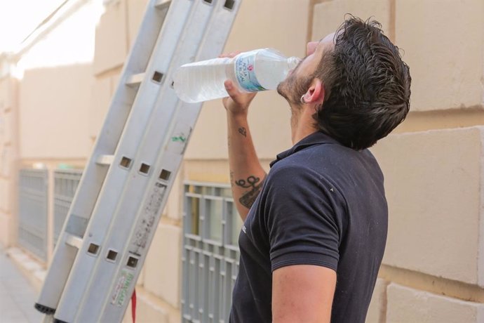 Un hombre bebe agua de una botella en un día de intenso calor.