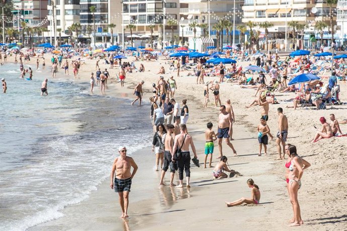 Archivo - Numerosas personas se bañan y toman el sol en la playa de Poniente en una imagen de marzo