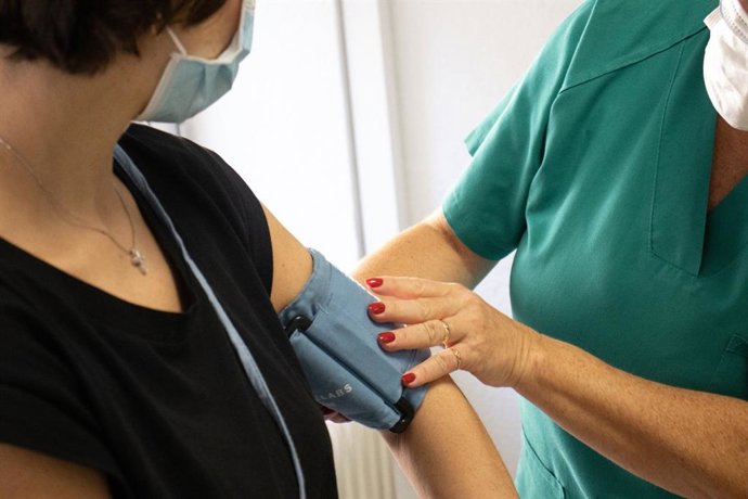 Archivo - Una sanitaria toma la tensión a una mujer