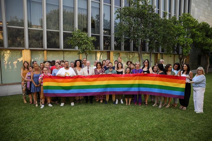El presidente de la Institución Provincial, Fernando Rodríguez Villalobos (c), y representantes de diversas entidades y asociaciones durante el despliegue de la bandera LGTBI+. A 27 de junio de 2023, en Sevilla (Andalucía, España). 