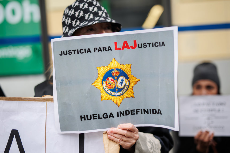 Una mujer sujeta una pancarta de 'Justicia para LAJusticia' a las puertas de la sede del Ministerio donde se reúnen el comité de huelga de los Letrados de Justicia y el Ministerio, a 27 de febrero de 2023, en Madrid (España).