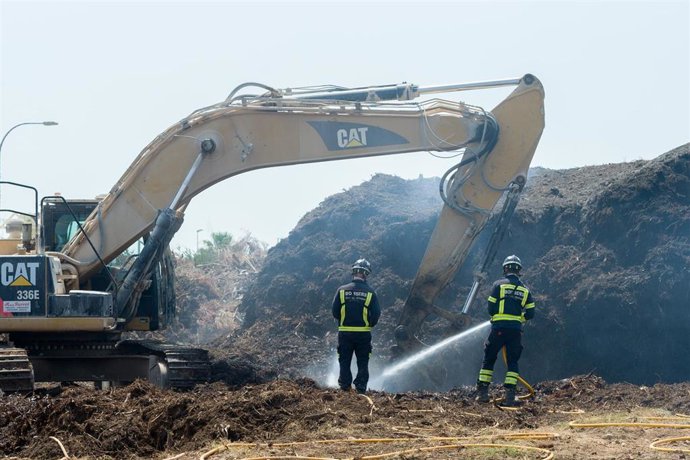 Bomberos y una máquina excavadora trabajan en la extinción del incendio de la planta de biomasa de Sant Rafel, a 27 de junio de 2023, en Ibiza