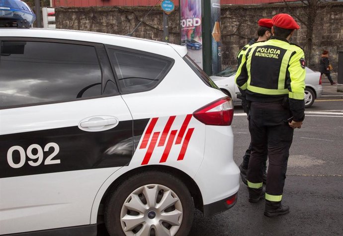 Archivo - Imagen de dos policías municipales junto a un coche de la Guardia Urbana.