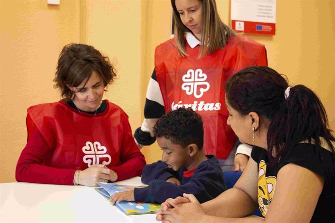 Un niño y su madre junto a dos técnicos de Cáritas en la sede del Centro de escucha de Cáritas Guadalajara.