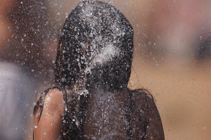 Una niña juega en el agua para refrescarse 