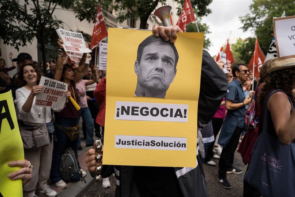 Funcionarios de justicia con una pancarta del presidente del Gobierno durante una protesta frente a la sede nacional del PSOE.