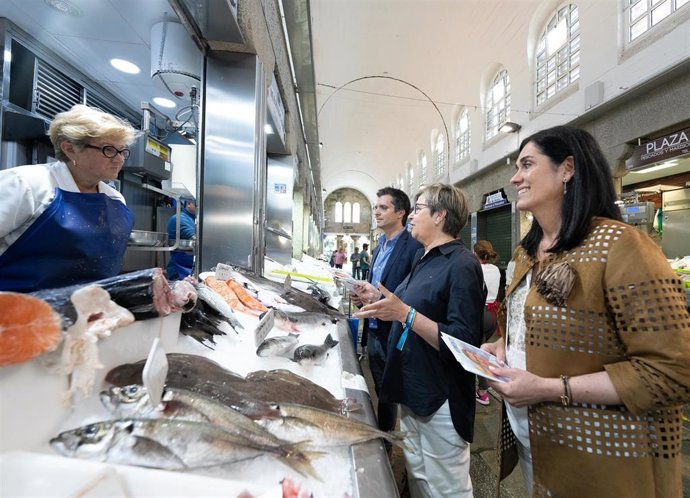 La secretaria general del PPdeG, Paula Prado, da un paseo por la Praza de Abastos de Santiago acompañada por la candidata del PP al Congreso Rosa Quintana y el líder del PP compostelano, Borja Verea.