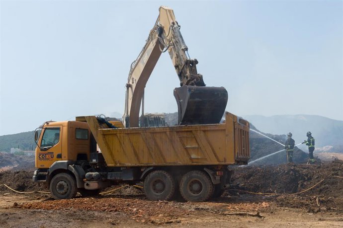 Bomberos y una máquina excavadora trabajan en la extinción del incendio de la planta de biomasa de Sant Rafel, a 27 de junio de 2023, en Ibiza