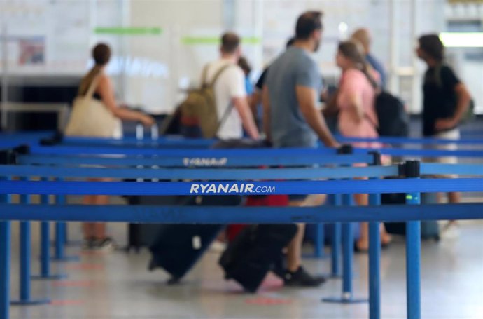 Archivo - Turistas hacen colas en los puestos de embarque de Ryanair, en una foto de archivo.