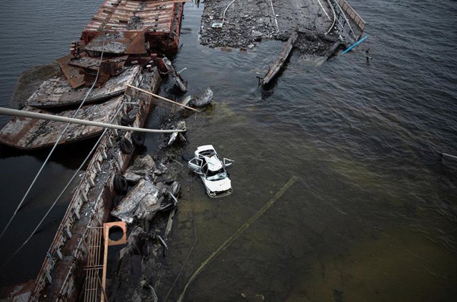Archivo - Un coche flota al lado de un puente destruido sobre el río Dniéper 