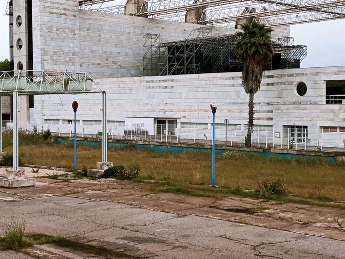 Archivo - Canal de los Descubrimientos de la Isla de la Cartuja, repleto de maleza y con el auditorio al fondo, en una imagen de archivo.