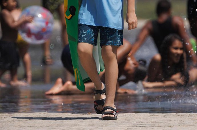 Varias personas juegan en el agua para refrescarse en Madrid Rio, a 26 de junio de 2023, en Madrid (España). 