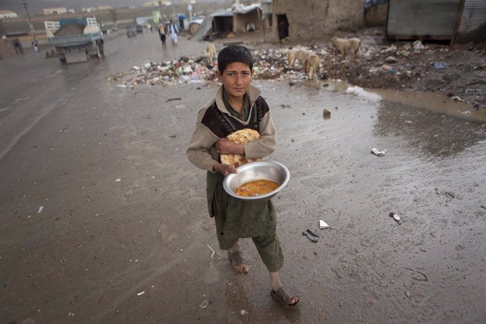 Archivo - Un niño recibe una ración de comida en su escuela de la capital de Afganistán, Kabul