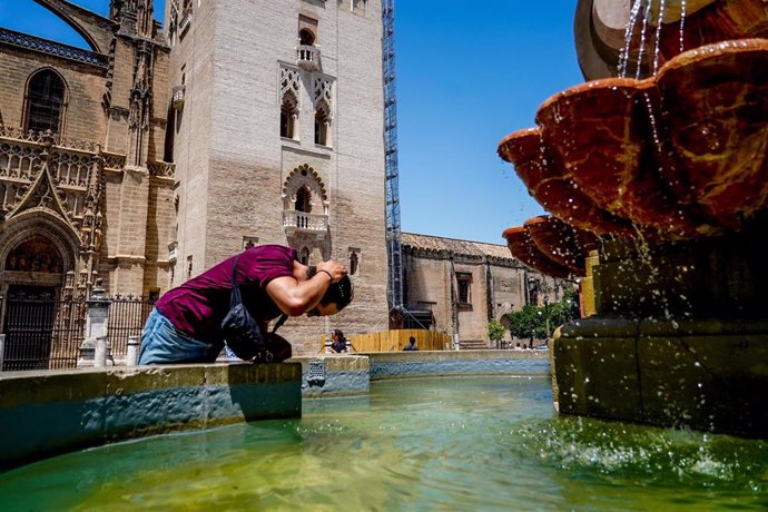 Un turista se refresca en una fuente de la Plaza Virgen de los Reyes en Sevilla (Andalucía). 