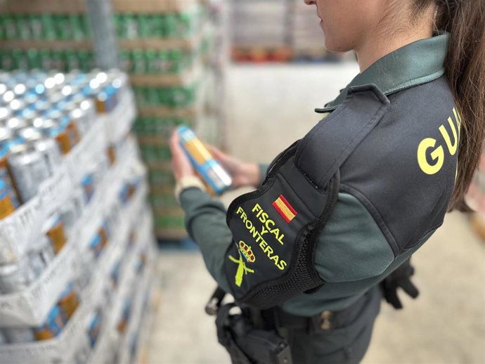 Una agente de la Guardia Civil con una de las bebidas decomisadas.