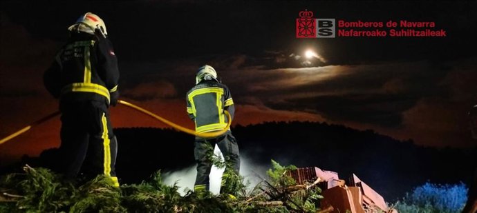 Efectivos de bomberos trabajan en la extinción del incendio de restos de poda junto a un campo de cereal sin cosechar en Berrioplano