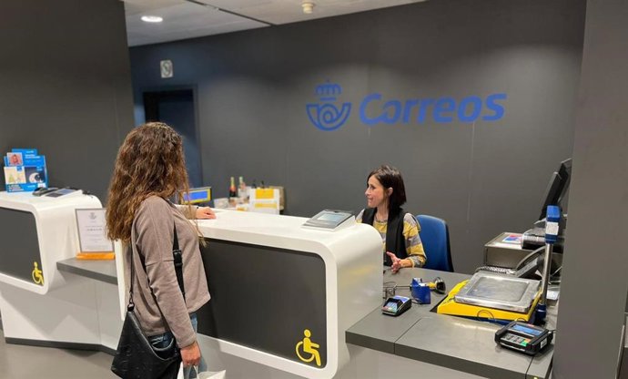 Archivo - Una mujer es atendida en la oficina de Correos Sur.