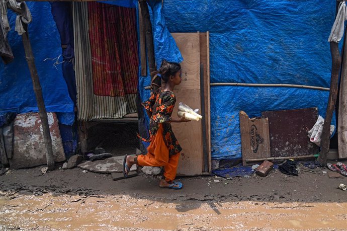 June 20, 2023, New Delhi, Delhi, India: A girls from the Rohingya Community runs through a muddy street caused by rains in a Rohingya Refugee Camp on World Refugee Day, in New Delhi, India on June 20, 2023.