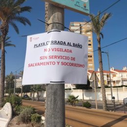 Imagen de un cartel en El Campello alertando del cierre al baño de la playa por la huelga de socorristas.