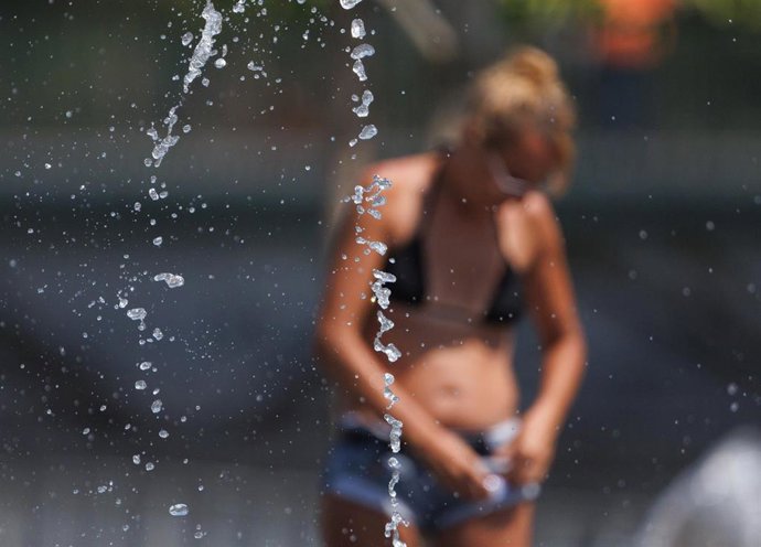 Varias personas juegan en el agua para refrescarse en Madrid Rio