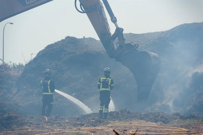 Bomberos y una máquina excavadora trabajan en la extinción del incendio de la planta de biomasa de Sant Rafel en una foto de archivo.