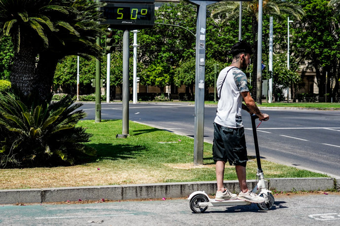Ciclista pasan por el termómetro situado en el Prado que marca 50 grados, a 26 de junio del 2023 en Sevilla (Andalucía, España). 