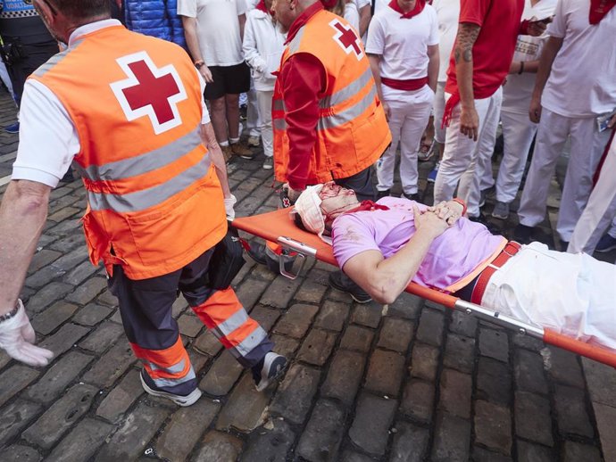 Voluntarios de Cruz Roja trasladan a un corredor herido en el cuarto encierro de los Sanfermines de 2023, protagonizado por toros de Fuente Ymbro.