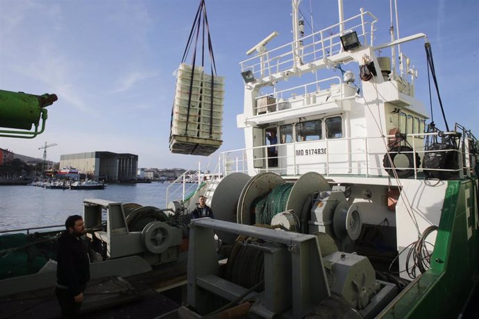 Archivo - Varios operarios sacan cajas con caballas de un barco.