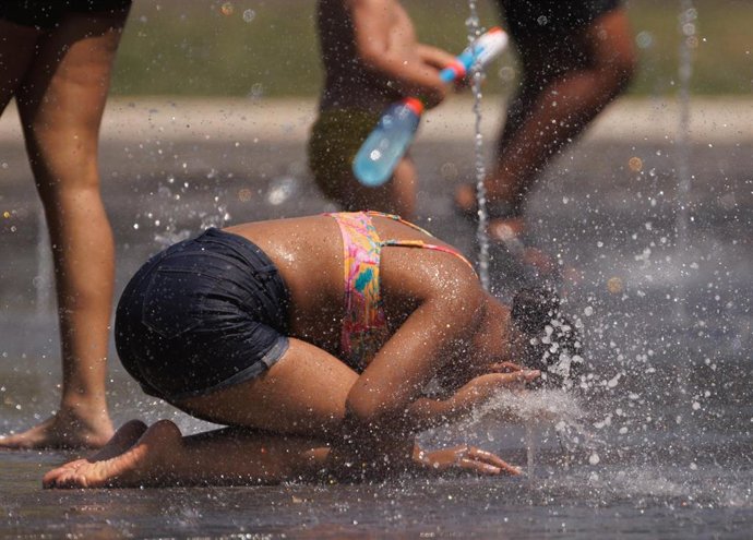 Varias personas juegan en el agua para refrescarse en Madrid Rio