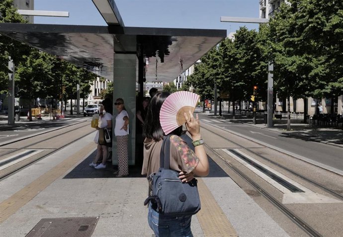 Una mujer se tapa del sol con un abanico en la parada del tranvía del Paseo de La Independencia, a 10 de julio de 2023, en Zaragoza, Aragón (España).