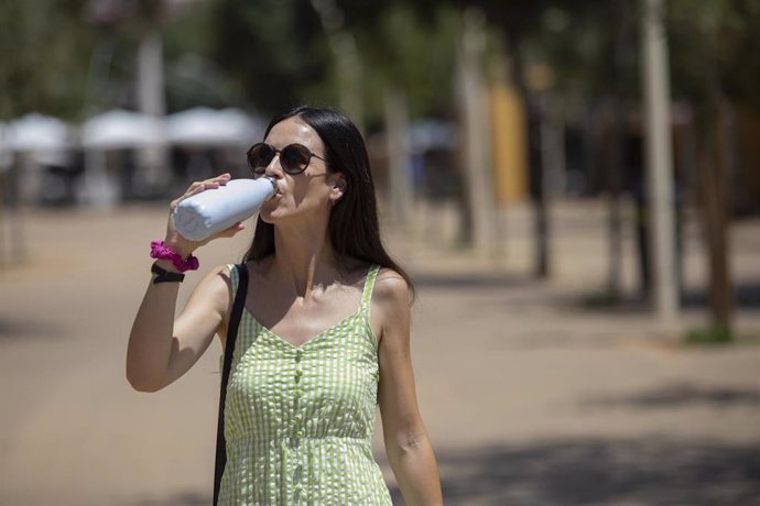 Una mujer con gafas de sol y botella de agua. Imagen de archivo.