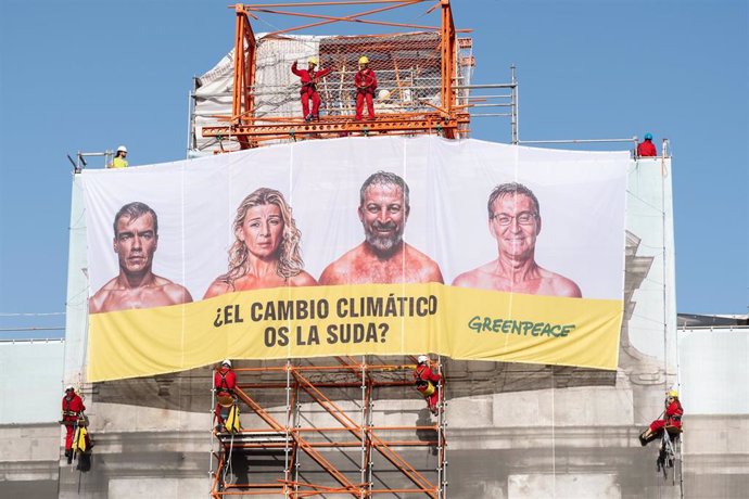 Varios activistas de Greenpeace cuelgan una lona en la Puerta de Alcalá, a 11 de julio de 2023, en Madrid (España).