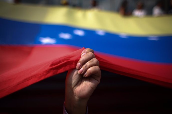 Archivo - dpatop - 12 March 2019, Venezuela, Caracas: A woman holds a Venezuelan flag during a demonstration against the government of incumbent President Nicolas Maduro amid massive power outages and the lack of water supplies. According to the oppositio